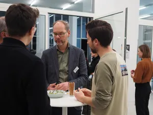 Professor im Gespräch mit Studierenden.