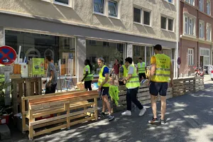 Students are building up a parklet with wood and plants.