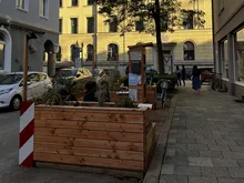 Ein Parklet aus Holz mit Sitzmöglichkeiten und einem Regal.